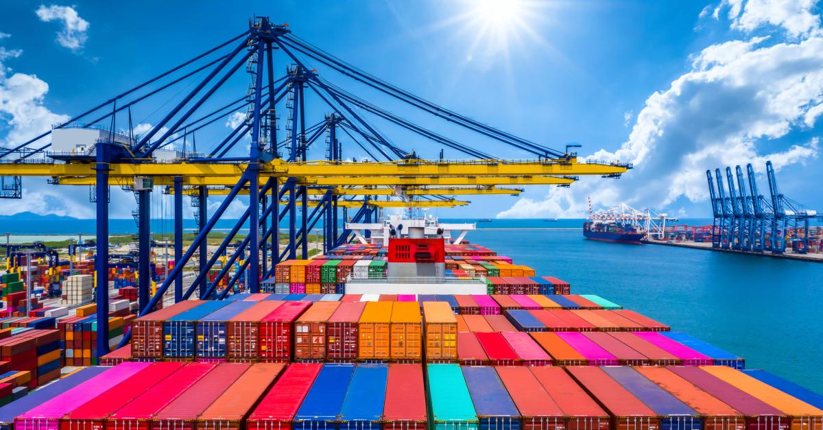 Shipping containers line up at a port waiting to be moved.