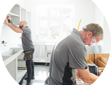 Two professionals installing cabinets in a customer’s kitchen.
