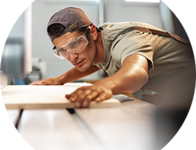 A craftsman with goggles preparing to cut a piece of wood.