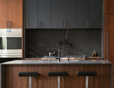 A modern, two-toned kitchen showcasing warm wood slab-style base cabinets, a matching island, and matte black upper cabinets.