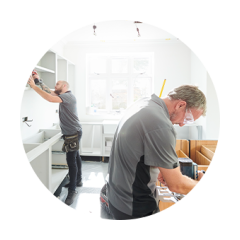 Two professionals installing cabinets in a customer’s kitchen.