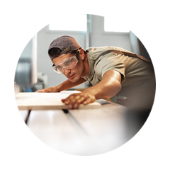 A craftsman with goggles preparing to cut a piece of wood.