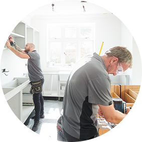 Two professionals installing cabinets in a customer’s kitchen.