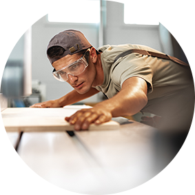 A craftsman with goggles preparing to cut a piece of wood.