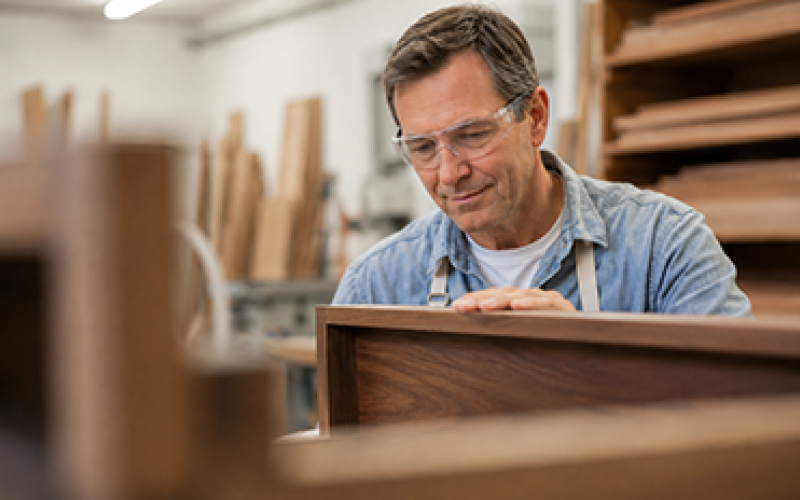 A craftsman examining a wooden drawer to meet strict cabinet standards.
